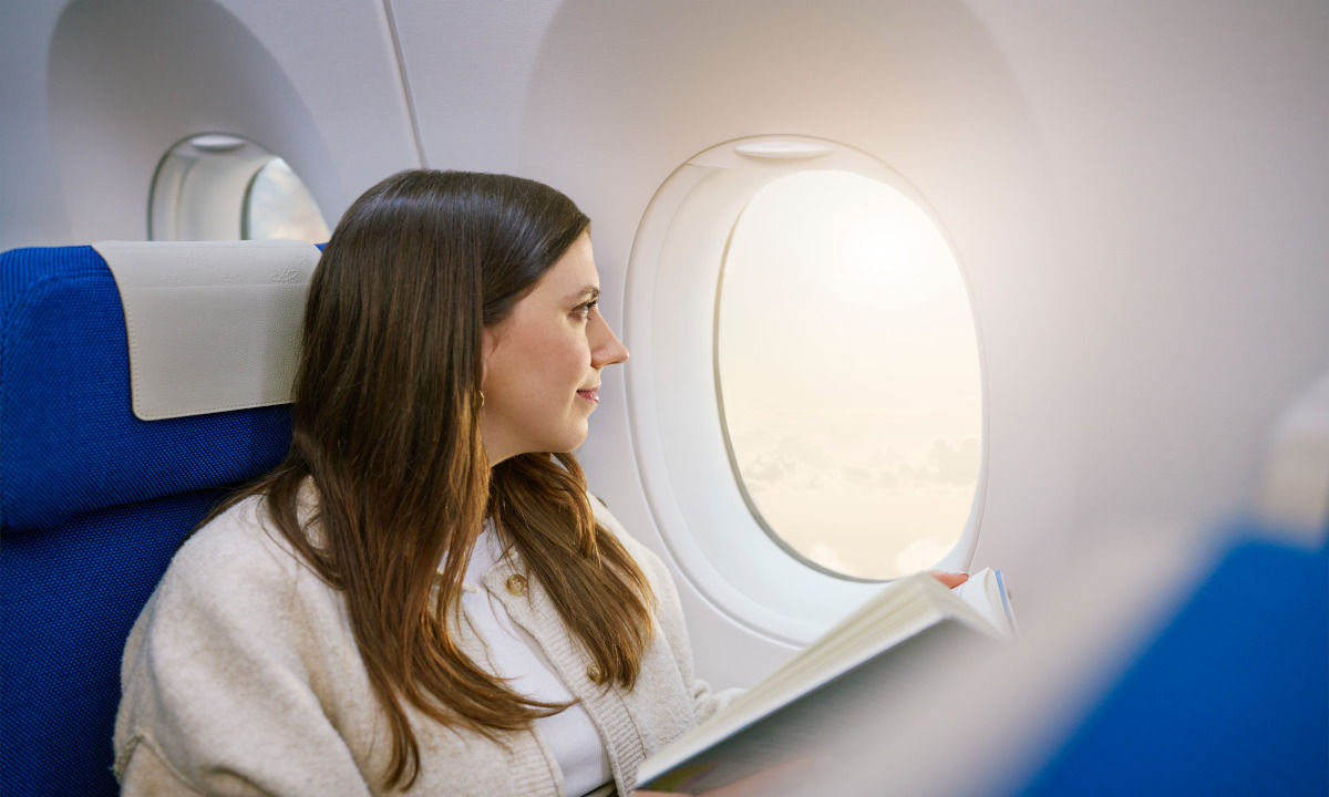 Frau schaut träumend aus dem Flugzeug Fenster