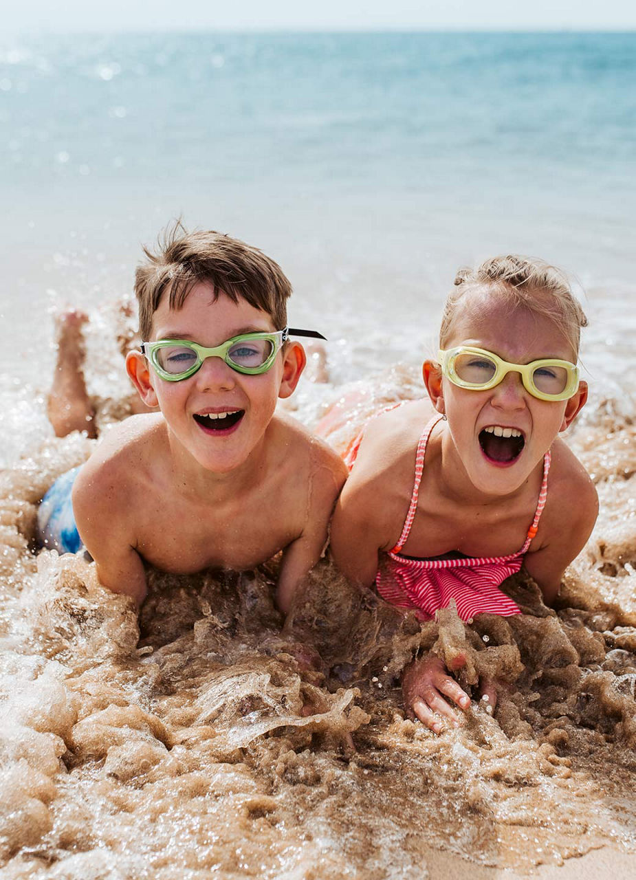 Junge und Mädchen liegen am Strand in den Wellen