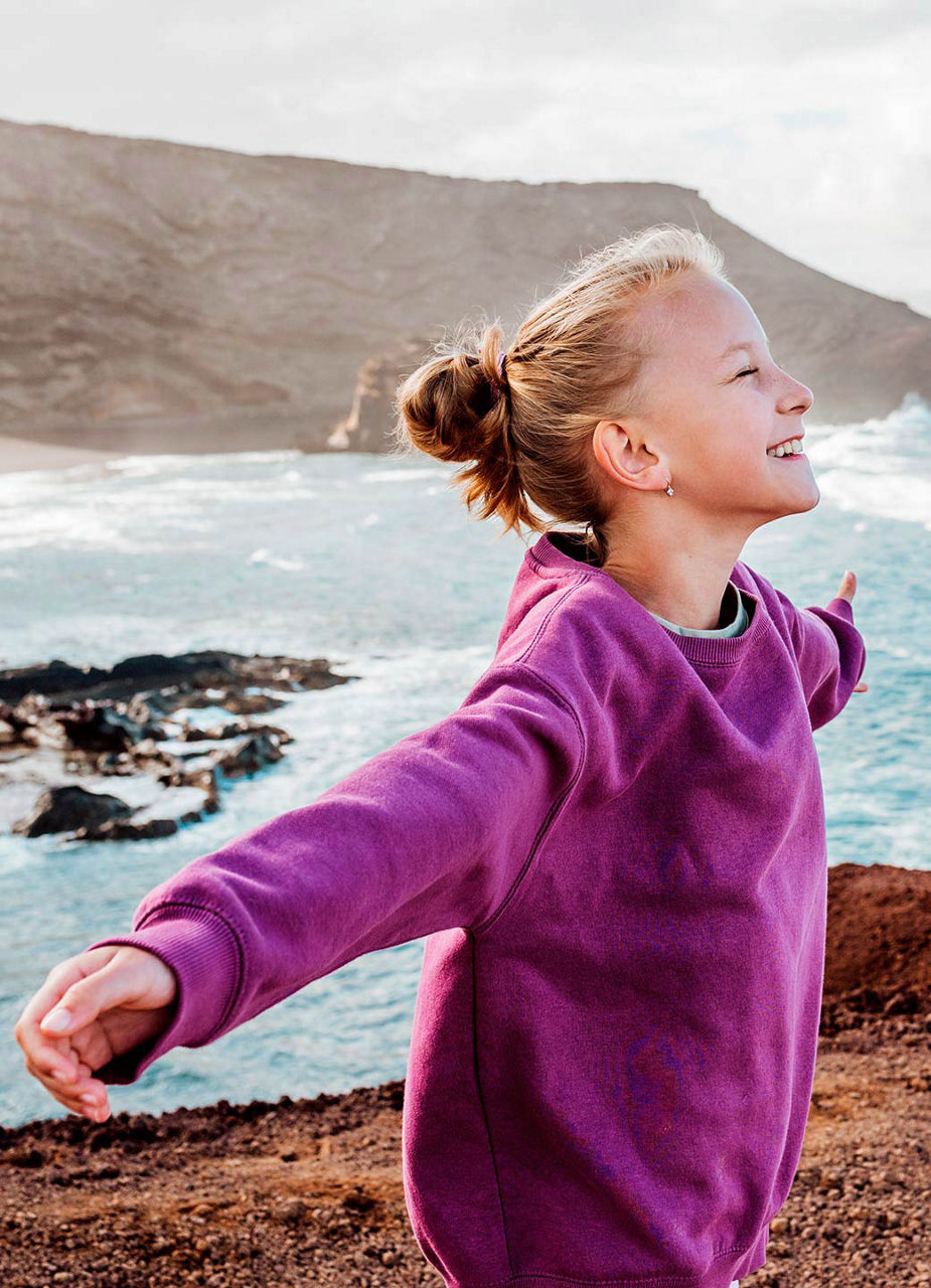 Mädchen steht auf den Klippen am Meer im Wird