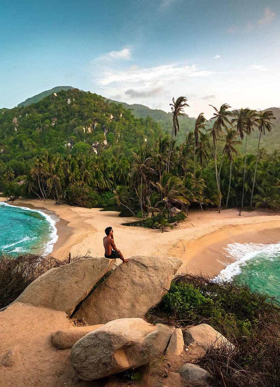 Man sitting on the beach with palm trees in the background