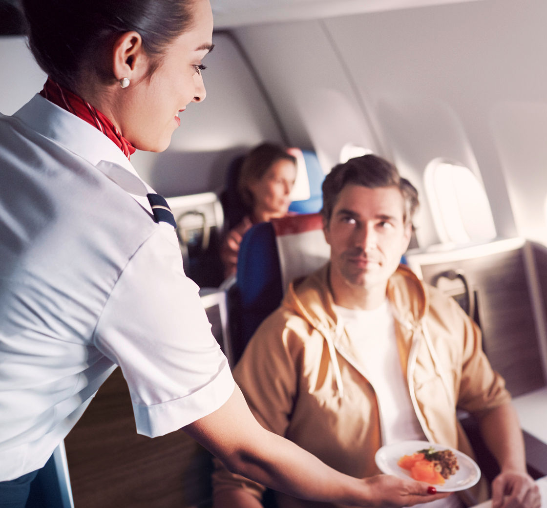 Flight attendant serves appetizer in business class