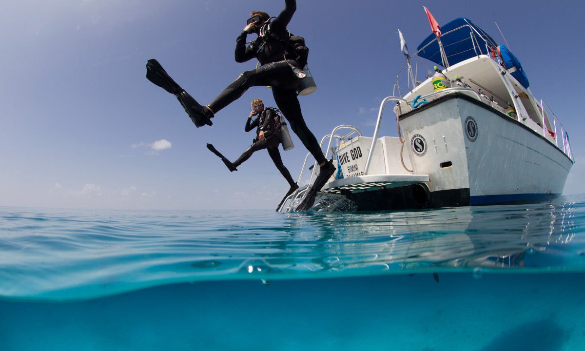 Two divers jumping from the boat into the water.