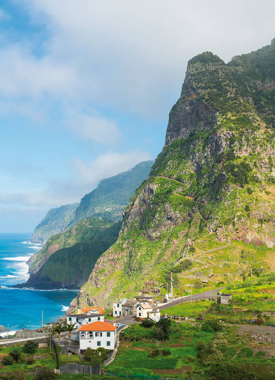 Montagne verte au bord de la mer avec des maisons devant