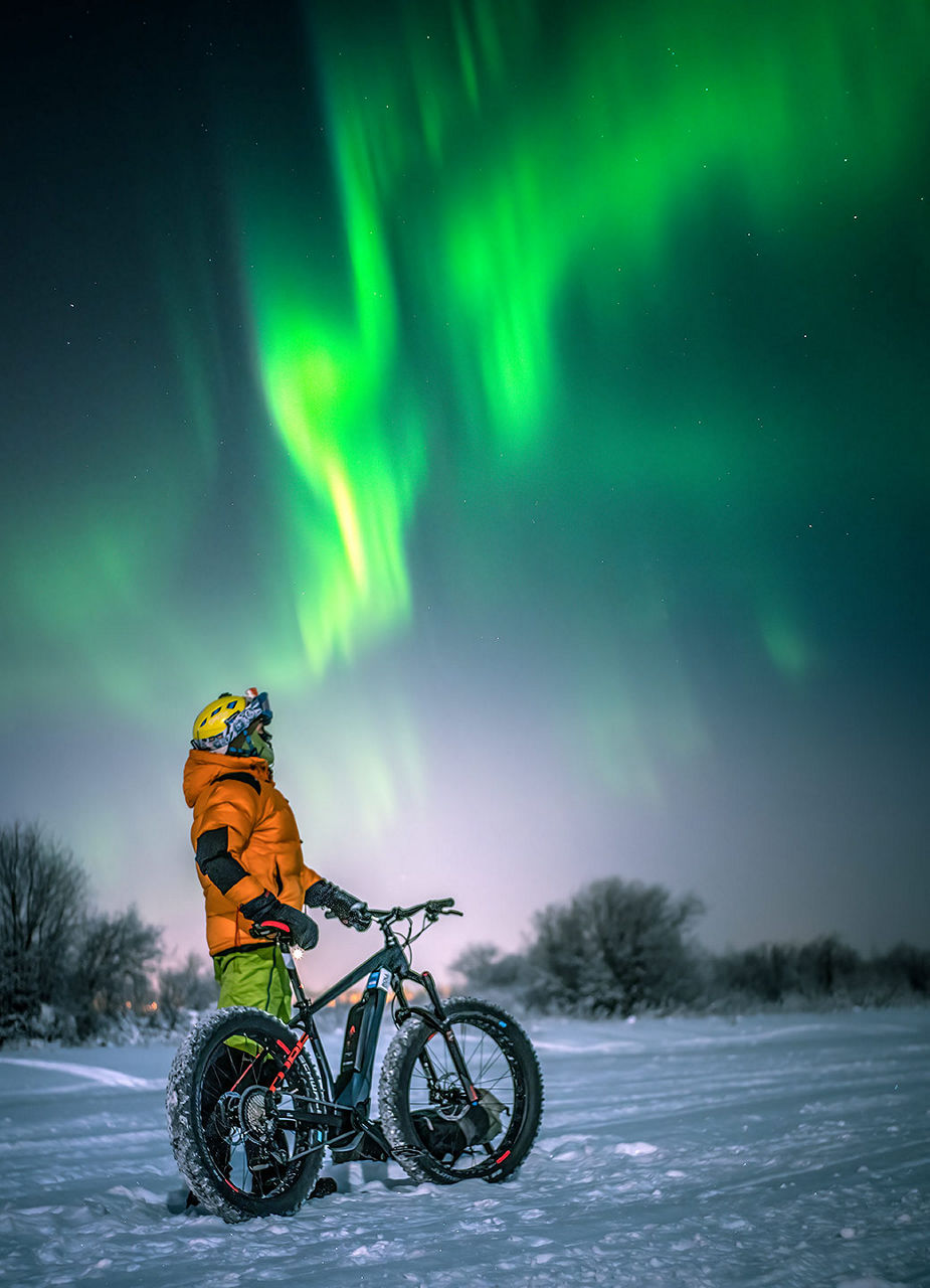 Man with bike and northern lights