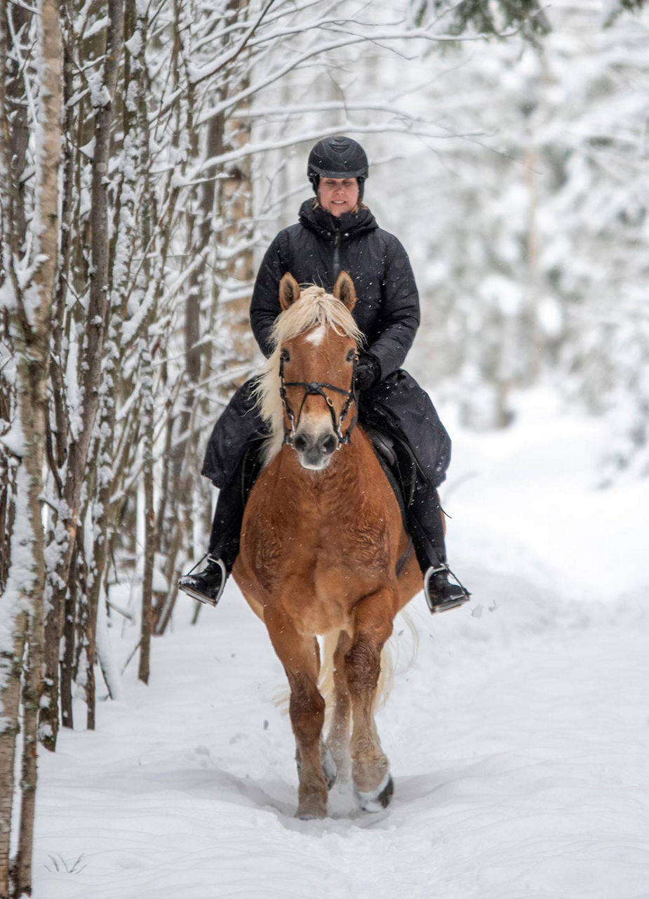 Frau reitet durch den Schnee