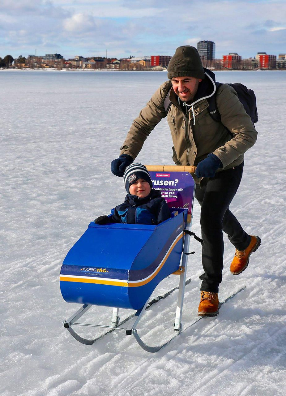 Mann mit Schlitten und Kind im Schnee