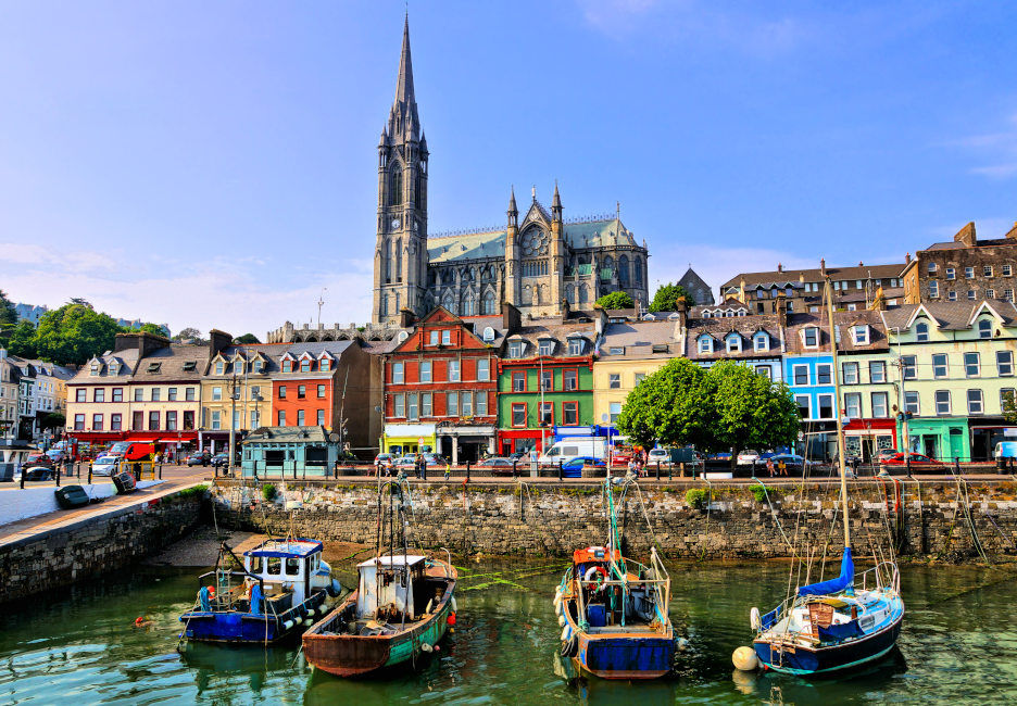 Kleine Boote im Hafen im Vordergrund, bunte Häuser und eine Kirche im Hintergrund