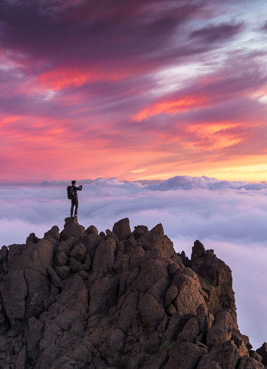 Human on mountain overlooking clouds