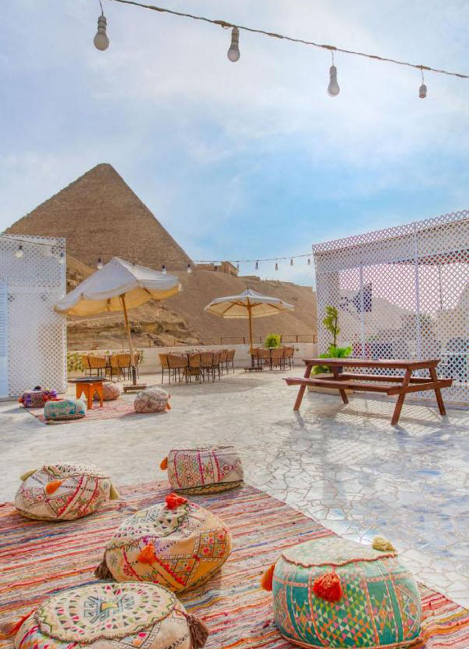 Teppich mit Sitzkissen im Vordergrund und den Pyramiden im Hintergrund