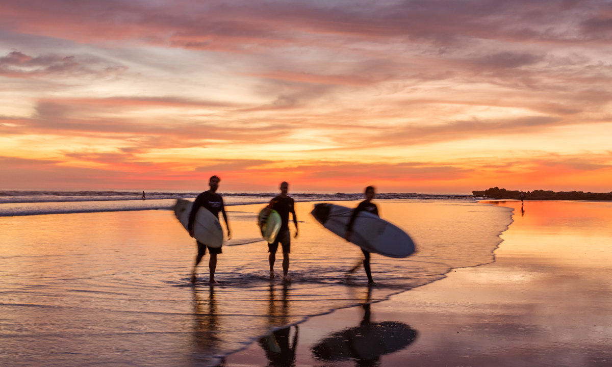 Trois surfeurs au coucher du soleil