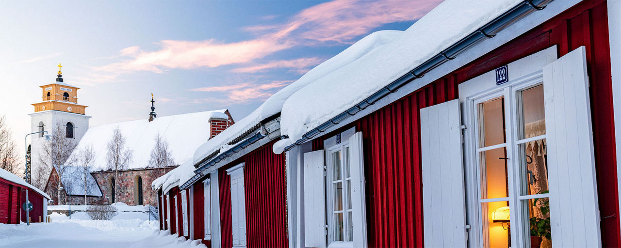 Arktischer Sonnenuntergang über den roten Holzhäusern in Gammelstad, Lulea, Schweden