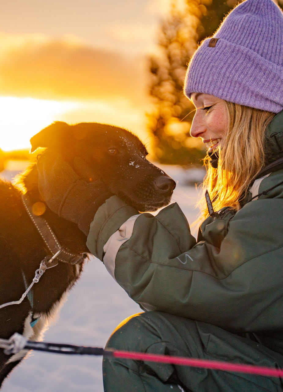 Chien et femme au coucher du soleil dans la neige