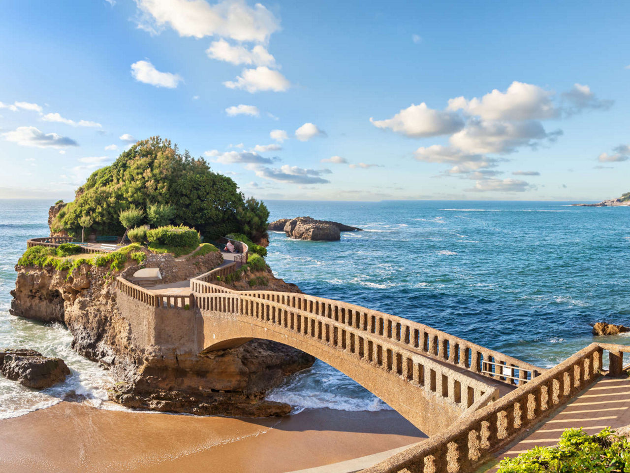 Pont de pierre menant à une île verte dans la mer