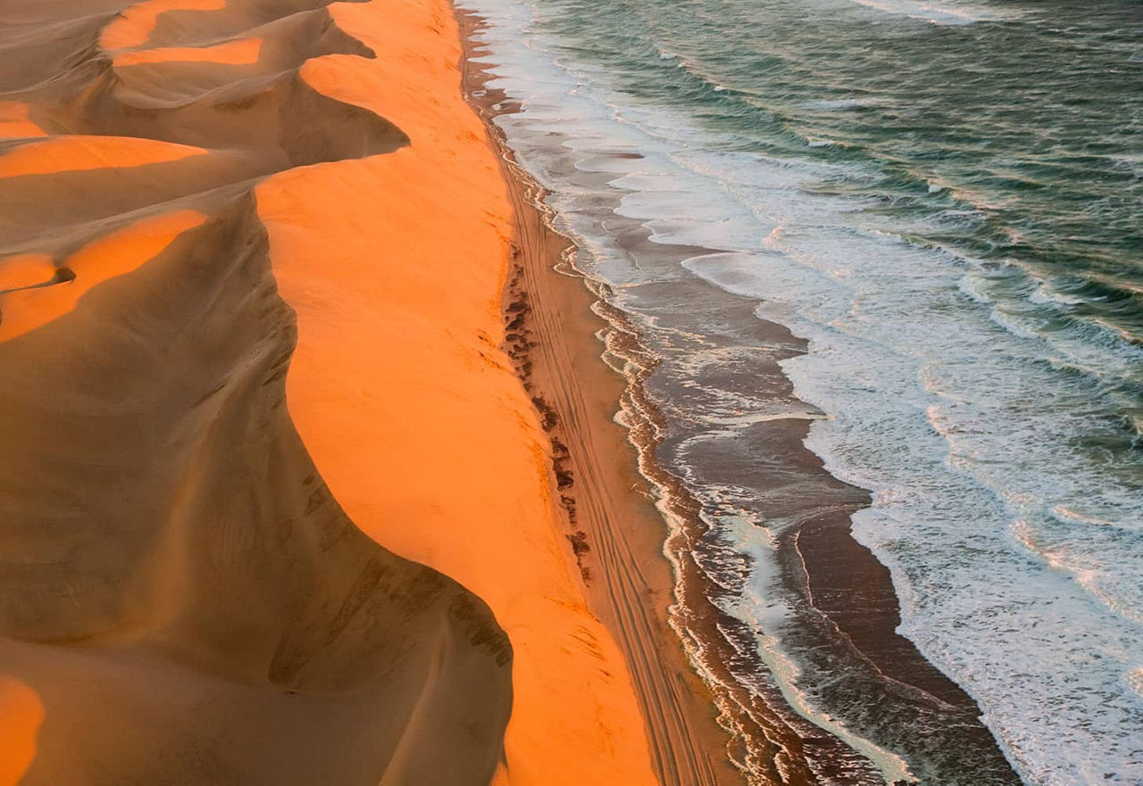 Dünen treffen auf das Meer in der Sandwich Harbour in Namibia
