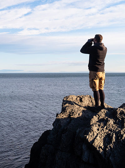 Mann schaut mit Fernglas auf das Meer​