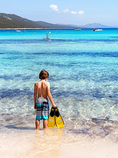 Junge mit Taucherflossen am Strand von Sakrun